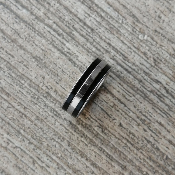 Anillo de acero inoxidable en color plateado acabado brillante y líneas negras. Ancho 7 mm.