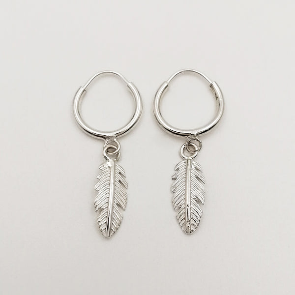 Argollas con cierre aguja, acabado liso con dijes plumas, en plata 925.